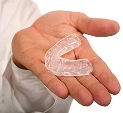 Hand holding a clear dental aligner or orthodontic retainer