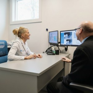 Patient consultation at dental office reception desk with computer and professional staff