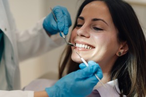 Dental professional wearing blue gloves performing a dental procedure on a patient's teeth
