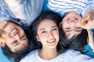 Group of smiling young people lying in a circle looking up at the camera