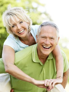 Cheerful senior couple posing together with woman hugging man from behind outdoors