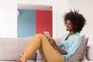 Woman with curly hair sitting comfortably on a couch in a colorful room with blue and red wall panels